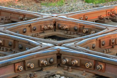 Rayların kesiştiği bir demiryolu hattı. İzler eski ve paslı ve onları bir arada tutan cıvatalar görünür durumda. İzler yıpranmış gibi görünürken sahne biraz kasvetli.