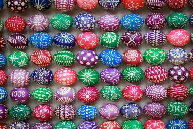 A bunch of painted eggs in various colors and designs. The eggs are arranged in a row and are of different sizes. Scene is cheerful and colorful, with the eggs being a fun and creative way to decorate clipart