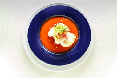 Altında beyaz bir plaka olan mavi bir tabak. Mavi tabakta bir kase yiyecek var.