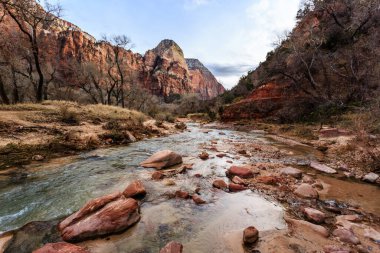 Kayalık bir kıyı şeridi ve arkasında dağlar olan bir nehir. Su temiz ve kayalar nehrin dört bir yanına dağılmış.