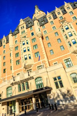 Üzerinde yeşil bayrak olan büyük bir bina. Bina kahverengi ve bir sürü penceresi var.