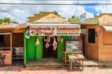 Üzerinde Carniceria y Lechoneria yazan küçük yeşil bir bina. Binanın önünde biraz et sergileniyor.