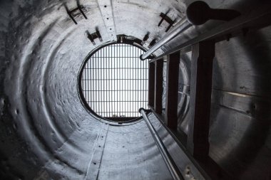 Bir tünelin ortasında bir merdiven görülür. Tünel karanlık ve tek ışık kaynağı merdiven.