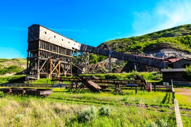 A large, old building with a red roof sits on a hillside. The building is surrounded by a fence and a grassy field. The scene has a nostalgic and peaceful mood, evoking a sense of history clipart