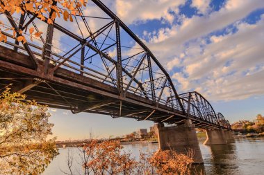 Bir köprü, güzel bir su ve gökyüzü manzaralı bir nehri kapsar. Köprü eski ve kırsal bir cazibesi var. Gökyüzü açık ve mavi, birkaç bulut etrafa saçılmış. Su sakin.