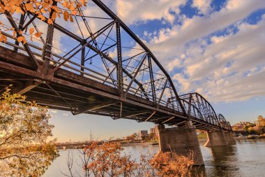 Bir köprü, güzel bir su ve gökyüzü manzaralı bir nehri kapsar. Köprü eski ve kırsal bir cazibesi var. Gökyüzü açık ve mavi, birkaç bulut etrafa saçılmış. Su sakin.