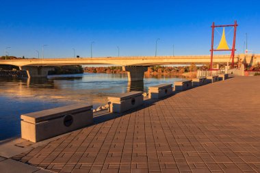 Bir köprü su manzaralı bir nehri kapsar. Köprü sıra sıra banklarla çevrili.