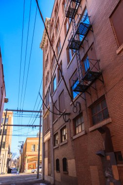 Yan tarafında yangın merdiveni olan tuğla bir bina. Bina yüksek ve birçok penceresi var.