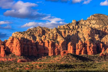 Dağlar kırmızı kayalarla kaplıdır ve gökyüzü mavidir. Dağlar çok yüksek ve gökyüzü berrak.