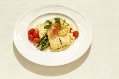 Üzerinde balık ve sebze olan bir tabak yemek. Tabak beyaz ve yemek renkli.