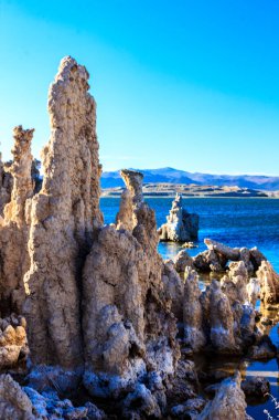 A rocky shoreline with a large rock formation and a body of water in the background. The scene is serene and peaceful, with the water reflecting the sky and the rocks creating a sense of stability clipart