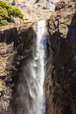 Bir şelale kayalık bir uçurumdan aşağı akıyor. Su berrak ve kayalar gri. Huzurlu ve huzurlu bir sahne.