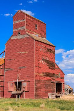 Arka planda mavi gökyüzü olan kırmızı bir tahıl ambarı. Silo eski ve kırsal bir görünüme sahip.