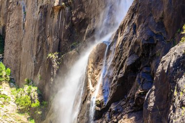 Bir şelale kayalık bir uçurumdan aşağı akıyor. Su beyaz ve sisli, sakin ve huzurlu bir atmosfer yaratıyor. Şelalenin etrafındaki kayalar pürüzlü ve pürüzlü.