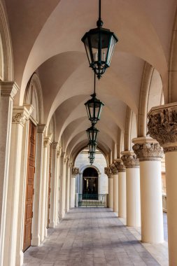 Tavanda beyaz bir tavan ve tavandan sarkan yeşil lambalar olan uzun bir koridor. Lambalar eşit aralıklı ve koridor çok uzun.