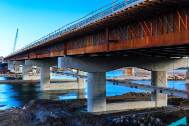 Bir nehrin üzerine bir köprü inşa ediliyor. Köprü beton ve çelikten yapılmıştır.