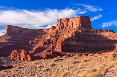 Arka planda bulutlu bir gökyüzü olan bir dağ sırası. Gökyüzü mavi ve dağlar kırmızı
