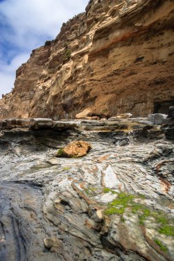 Üzerinde küçük bir kaya olan kayalık bir uçurum. Kaya yosunla kaplı. Uçurum bir dağ sırasının parçasıdır.