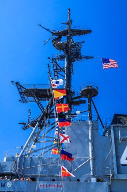 Üzerinde bir sürü bayrak olan büyük bir gemi. Bayraklar farklı renk ve boyutlarda. Gemi okyanusta ve gökyüzü açık.