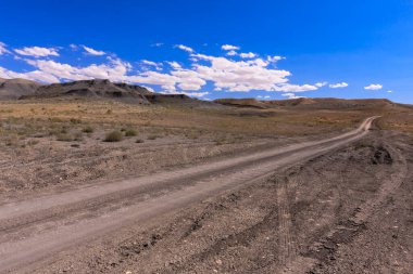Arka planda mavi gökyüzü olan çölde bir yol. Yol boş ve gökyüzü temiz.