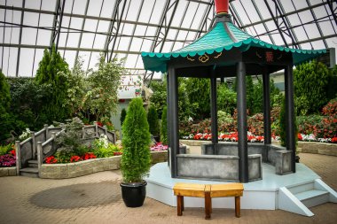 Önünde bir bank ve saksı bitkisi olan küçük bir pavyon. Çadırın etrafı bir sürü ağaç ve çiçekle çevrili.