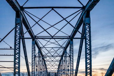 Arka planda mavi gökyüzü olan bir köprü. Köprü eski ve paslı.