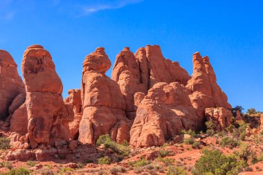 Arka planda mavi gökyüzü olan kayalık bir dağ sırası. Dağlar uzun ve kayalıktır ve bazıları sivri bir şekle sahiptir. Sahne huzurlu ve sakin, dağlar dik duruyor.