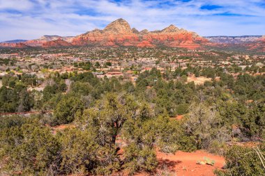 Uzakta bir kasabası olan bir dağ sırası. Gökyüzü mavi ve ağaçlar yeşil