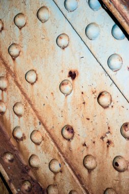 Görüntü, pek çok küçük deliği olan paslı bir metal yüzeye ait. Delikler tüm yüzeye saçılmış ve metal eski ve aşınmış görünüyor. Sahne çürüme ve ihmalkarlıktır.