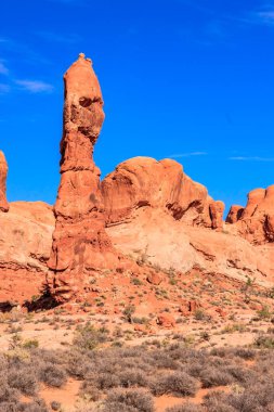 Çölün ortasında büyük bir kaya oluşumu bulunur. Gökyüzü açık ve mavidir, ve güneş parlıyor. Huzurlu ve huzurlu bir sahne.