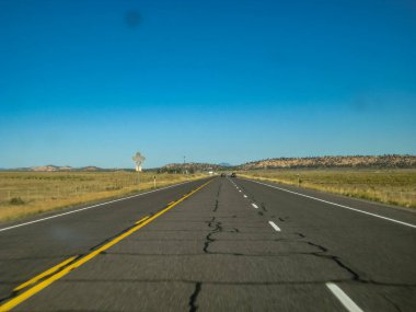 Üzerinde birkaç araba olan uzun, boş bir otoyol. Gökyüzü açık ve mavi