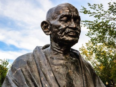 Mahatma Gandhi 'nin bir heykeli parkta oturuyor. Heykel bronzdan yapılmıştır ve çok ayrıntılıdır. Gökyüzü mavi ve arka planda bazı bulutlar var