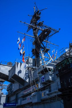 Direğinde bayraklar olan büyük bir gemi. Bayraklar farklı renk ve boyutlarda. Gemi okyanusta ve gökyüzü açık.