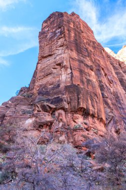 Arka planda mavi gökyüzü olan bir dağ. Dağ çok yüksek ve bir sürü kayası var.
