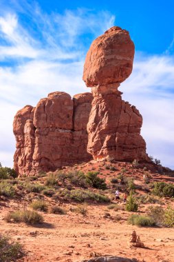 Üzerinde küçük bir tepe olan büyük bir kaya oluşumu. Gökyüzü mavi ve arka planda bulutlar var.