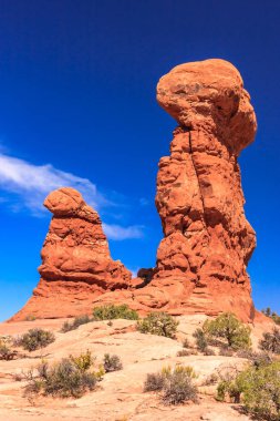 Üzerinde küçük bir kaya olan büyük bir kaya oluşumu. Gökyüzü mavi ve hiç bulut yok.