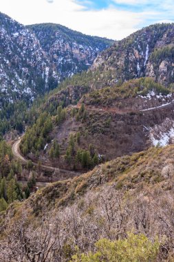 Karla kaplı dolambaçlı bir yolu olan bir dağ sırası. Yol ağaçlarla çevrili ve dağlar karla kaplı. Huzurlu ve huzurlu bir sahne.