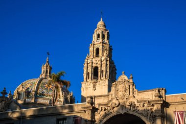 Tepesinde kubbe ve çan kulesi olan büyük bir bina. Bina ağaçlarla çevrili ve arka planda mavi bir gökyüzü var.