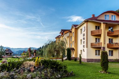 Büyük yeşil çimenli ve havuzlu bir otel. Otel güzel bir dağ manzarasında yer almaktadır.