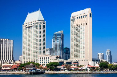 İki büyük oteli ve büyük bir su kütlesi olan bir şehir silueti. Gökyüzü açık ve mavi