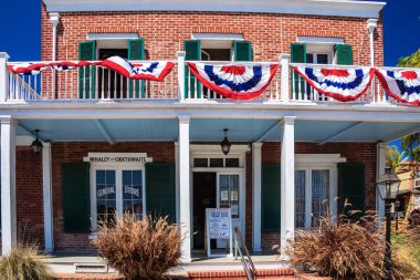 Balkonunda kırmızı, beyaz ve mavi bir pankartı olan tuğla bir bina. Pankartta 