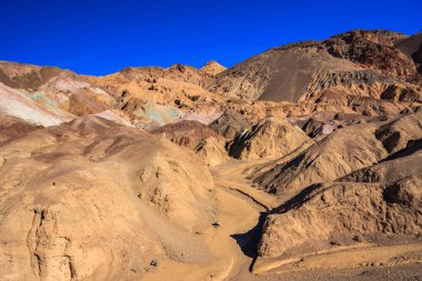 Aralarında vadi olan bir dağ sırası. Vadi kayalar ve toprakla dolu. Gökyüzü mavi ve berrak