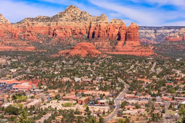 Arkasında dağ olan bir şehir. Dağ kırmızı ve şehir çoğunlukla kahverengidir.