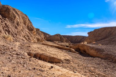 Kuru nehir yatağı olan bir çöl manzarası. Gökyüzü açık ve mavi. Boşluk ve yalnızlık kavramı
