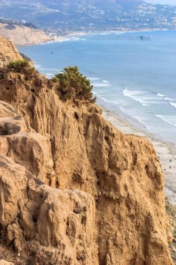 Kayalık bir uçurum sahil boyunca birkaç kişinin yürüdüğü bir sahile bakar. Sahne huzurlu ve sakin, arka planda dalgaların çarpma sesi var. Kayalık uçurumun birleşimi