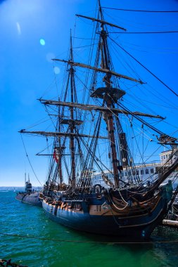 Direğinde kırmızı bayrak olan büyük bir gemi. Gemi bir limana yanaştı.