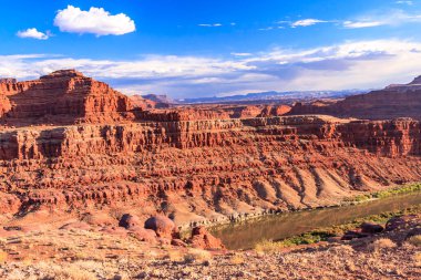 İçinden bir nehrin aktığı güzel bir manzara. Gökyüzü açık ve mavidir, ve güneş parlıyor. Arka plandaki dağlar, sahnenin ihtişamını ve ihtişamını arttırır.