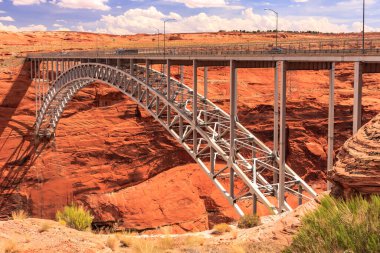 Bir köprü çöl manzaralı bir kanyonu kapsar. Köprü metalden yapılmıştır ve bir nehrin üzerinde asılıdır.