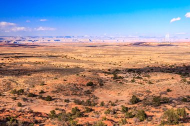 Arka planda mavi gökyüzü olan bir çöl manzarası. Gökyüzü açık ve güneş parlıyor.