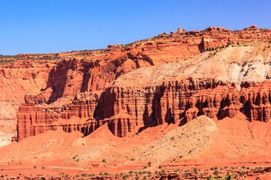 Arka planda mavi gökyüzü olan güzel, kayalık bir manzara. Kayaların boyutları ve şekilleri farklıdır. Arazi engebeli ve düzensizdir.